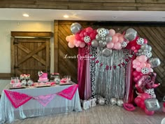 a table topped with lots of pink and silver balloons