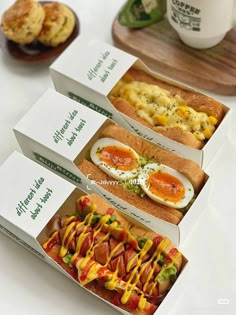 three boxes filled with different types of food on top of a white table next to cupcakes