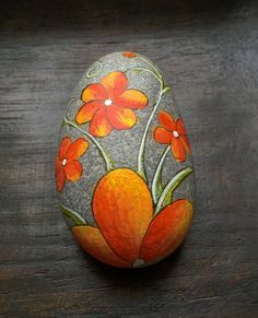 an orange painted rock with flowers on it