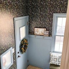 a blue door in a room with floral wallpaper