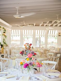 the tables are set with white linens and colorful flowers