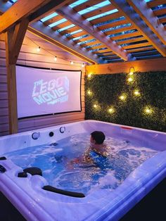 a man in a hot tub watching a movie on the wall behind him is a projector screen