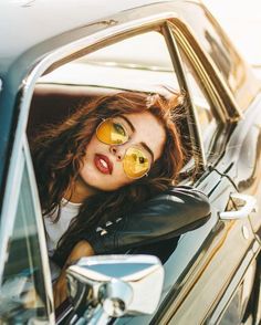 a woman wearing yellow sunglasses sitting in a car