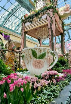 a tea cup in the middle of a garden filled with flowers