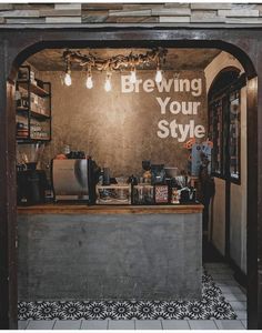 the inside of a coffee shop with lights hanging from the ceiling and signs on the wall