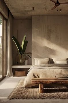 a bedroom with a large bed sitting next to a window and a plant in the corner