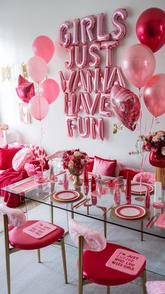 a table with pink chairs and balloons on the wall behind it that says girls just wanna fun