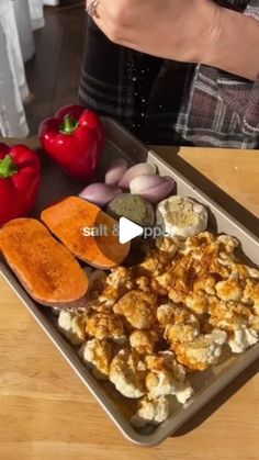 a person standing in front of a tray filled with different types of food and vegetables