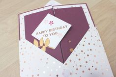 a birthday card with gold foil on the inside of it and a pink envelope in the middle