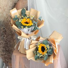 two sunflowers are wrapped in brown paper and tied with white ribbon on a table