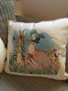 two pillows on a couch with an image of rabbits and a duck