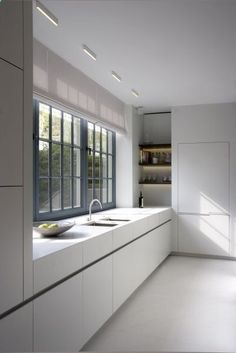 a large kitchen with white cabinets and counter tops next to a window that looks out onto the outdoors