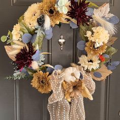 a wreath with sunflowers and feathers hanging on a door