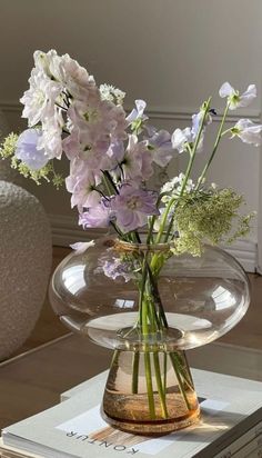 a vase filled with flowers sitting on top of a table next to a stack of books