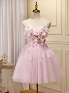 Reminiscent of a pastel masterpiece, this homecoming dress delights with its array of soft pink hues and floral accents. The bodice, fitted to perfection, is a canvas for the intricately placed flowers that seem to drift effortlessly across the fabric. The skirt fans out in gentle folds of tulle, creating a romantic and graceful profile that will twirl beautifully to the rhythm of the music. Ideal for a homecoming queen, this dress is a blend of elegance, youth, and charm. Pink Bustier Dress, Kawaii Homecoming Dress, Pink Party Dress Short, Short Pink Prom Dress, Pink Prom Dresses Short, Beading Applique, Prom Dress Cute, Strapless Homecoming Dresses, Vestidos Color Rosa