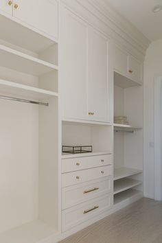 an empty closet with white cabinets and drawers