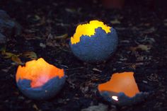 three painted eggs sitting on the ground with one egg broken in half and another cracked