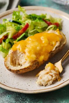 a white plate topped with food and a salad next to a fork on a table