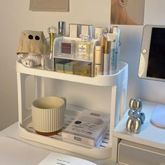 a white shelf filled with cosmetics and personal care items on top of a table next to a computer