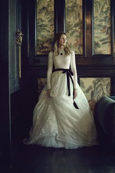 a woman in a long white dress is posing for the camera