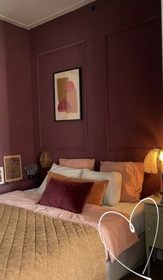 a large bed sitting next to a window in a room with purple walls and wooden floors