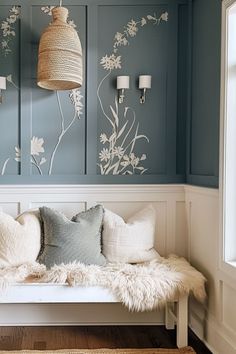 a white bench sitting in front of a wall with flowers painted on it and two lamps