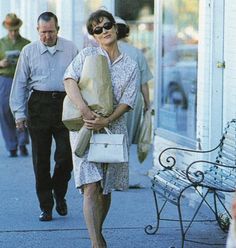 an older woman walking down the street carrying bags