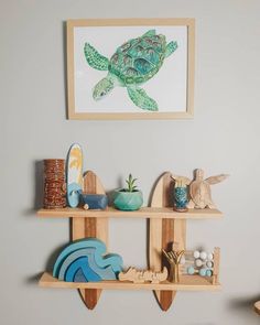 two wooden shelves with various items on them and a framed turtle painting above the shelf