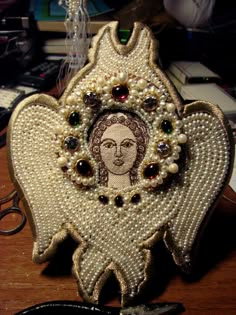 an angel brooch with pearls and jewels on it's wings is sitting on a table