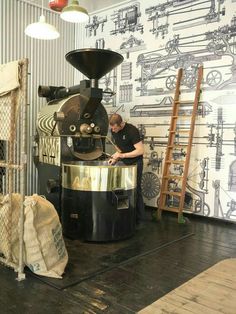 a man standing in front of a coffee grinder on top of a wooden floor