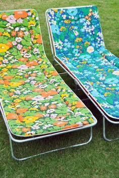 two lawn chairs sitting on top of a lush green grass covered field next to each other