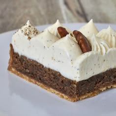 a piece of cake on a white plate with frosting and nuts in the middle