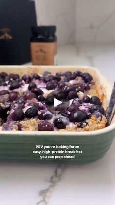 a blueberry cobbler is shown in a green casserole dish