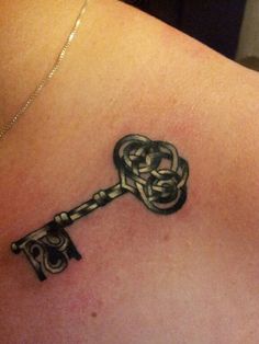 a tattoo on the back of a woman's shoulder with a key attached to it