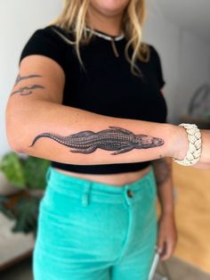 a woman is showing off her arm with a lizard tattoo on it's arm