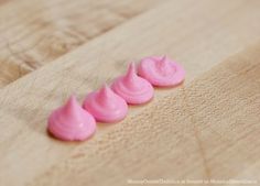 three pink jellos sitting on top of a wooden table next to each other