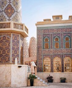 a man standing in front of a tall building with intricate designs on it's walls