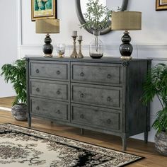 a room with a rug, mirror and two vases on the floor next to a dresser