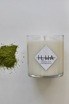 a white candle sitting next to a pile of green powder