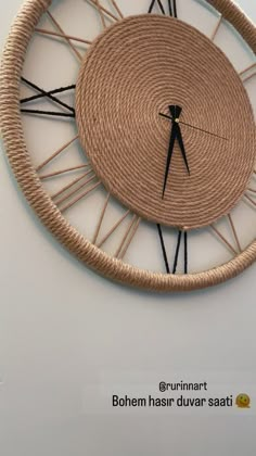 a clock made out of rope on the side of a white wall with black hands