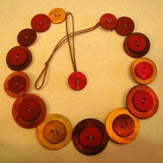 a necklace made out of wooden buttons on a white surface with string attached to it