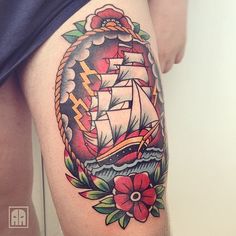 a woman's thigh with a ship and flowers tattoo design on the side of her leg