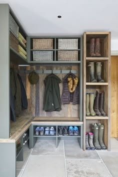 a walk in closet with lots of boots and coats on the shelves next to it