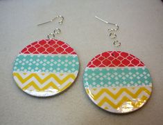 two pairs of earrings with colorful designs on them sitting on top of a white surface