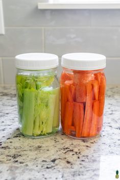 two jars filled with vegetables sitting on top of a counter