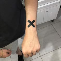 a person with a black cross tattoo on their wrist