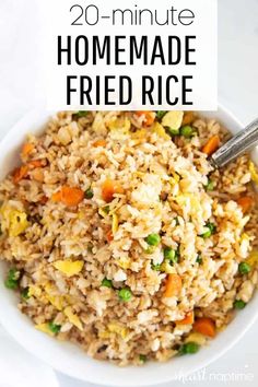 a white bowl filled with fried rice and carrots next to a fork in it