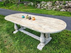 a wooden table with three vases on it sitting in the grass next to a road