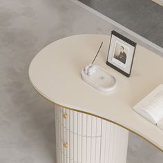 a white table with a book and an electronic device on it next to a framed photo