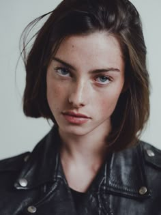 a young woman with freckled hair and blue eyes wearing a black leather jacket